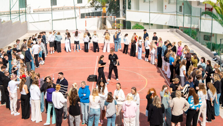 Elever står i rundkreds omkring Utopia-instruktører i midten, der underviser på guideskolen.